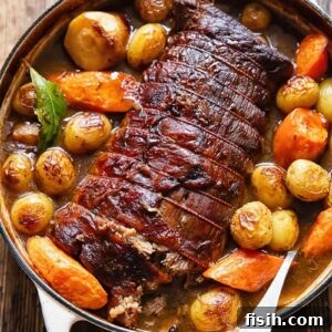 Top down shot of beef pot roast with potatoes and carrots, ready to serve, showing rich gravy.