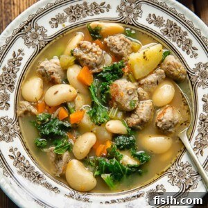 Top-down view of a bowl of White Bean and Sausage Soup with a spoon, featuring tender sausage and creamy white beans in a rich, herby broth.