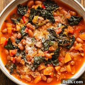 Close-up of a bowl of Chorizo Bean and Vegetable Soup, topped with grated Parmesan, featuring chunky vegetables and borlotti beans infused with vibrant red chorizo oil.