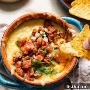 tortilla chip being dipped into dish of queso fundido with chorizo