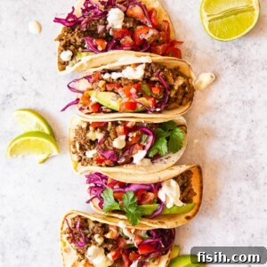 Ground Beef Tacos topped with salsa, avocado slices and red cabbage slaw.