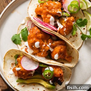 Buffalo cauliflower tacos folded and leaning together on a plate