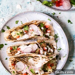 three tacos on a plate with fillings including vegetables and sauces
