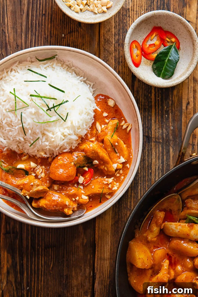 a beautifully arranged serving of Panang Chicken Curry with rice in a bowl on a rustic wooden background