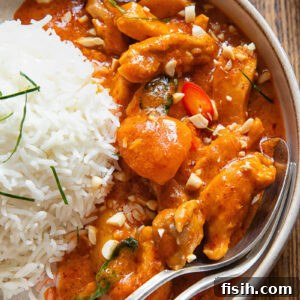 close view of curry in a bowl next to a ball of rice, with a spoon and fork