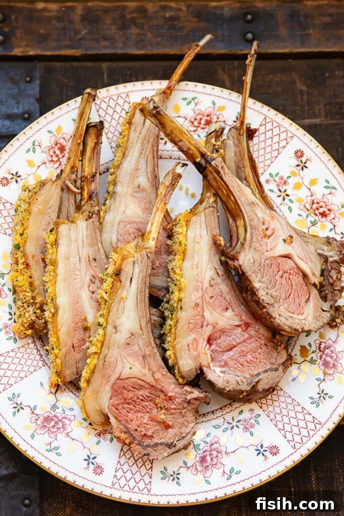 Perfectly roasted rack of lamb slices adorned with a vibrant pistachio, herb, and garlic crumb, served on a white plate ready to be enjoyed as a gourmet meal.