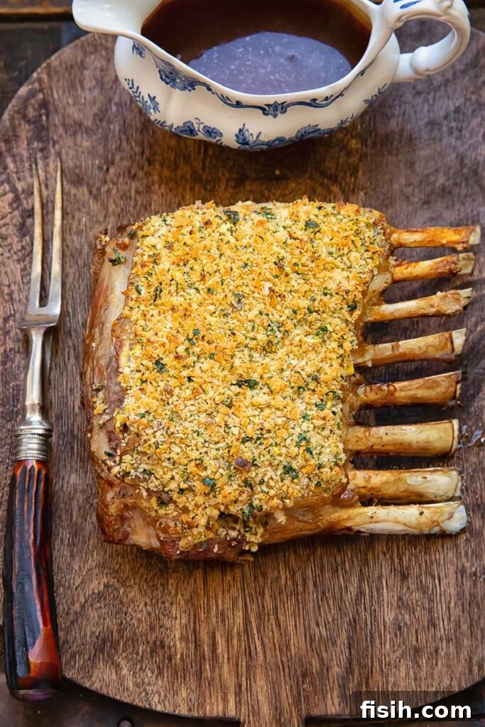 A perfectly roasted rack of lamb, featuring a golden-brown pistachio herb crust, resting on a wooden cutting board before being carved into individual chops.