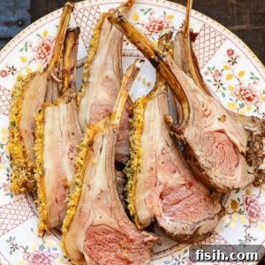 A serving of perfectly roasted rack of lamb with pistachio herb and garlic crumb on a white plate, garnished and ready to eat.