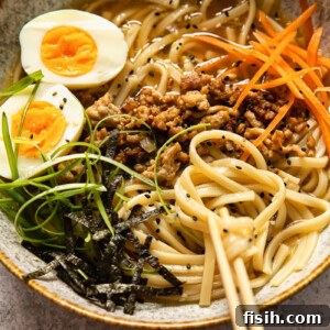 udon noodle soup topped with ground pork, boiled egg, green onion and carrots