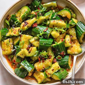 Top down shot of smashed cucumber salad in a bowl with a spoon
