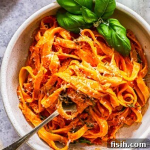 Top down of a bowl of pasta with basil and tomato and mascarpone basil sauce