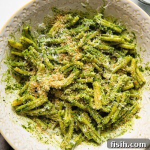 pesto pasta in a serving bowl with grated parmesan next to it