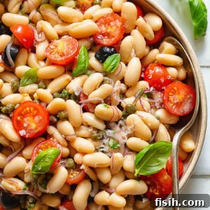 Top down shot of white bean salad in a serving bowl with basil garnish