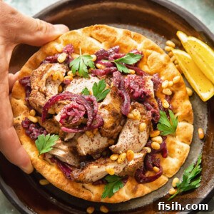 Person grabbing Chicken Musakhan on flatbread