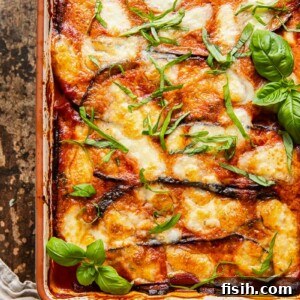 top down view of eggplant parmesan in a rectangular pan on dark background