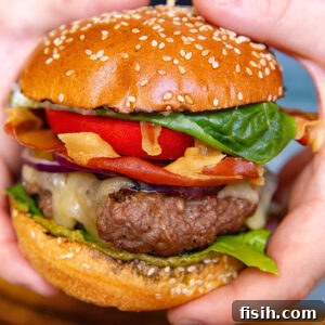 Italian Prosciutto Burger with Garlic Parmesan Mayo 5 A vertical shot of a beef patty, tomato, lettuce and prosciutto in a bun in hands