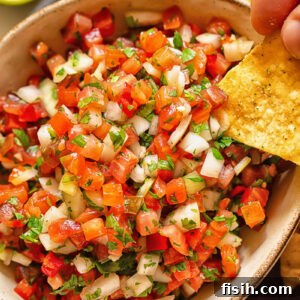 Close up shot of tortilla chip dipped in pico de gallo