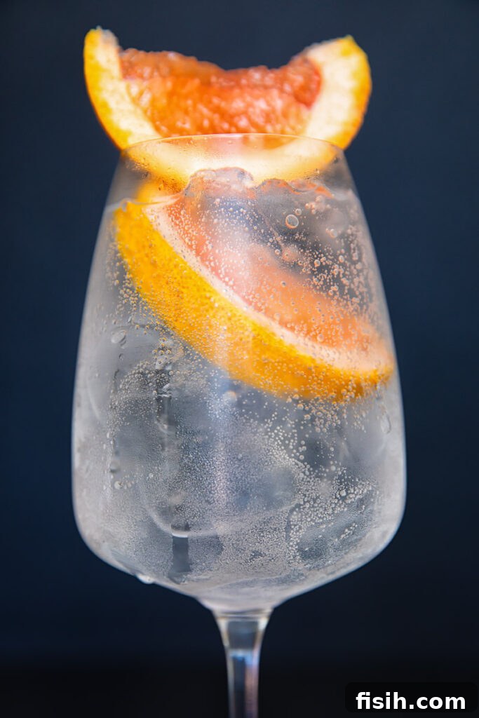 Close up of a wine glass with the spritz with two prominent slices of grapefruit on top.