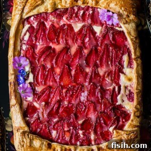 View of strawberry galette with pink flowers as decoration