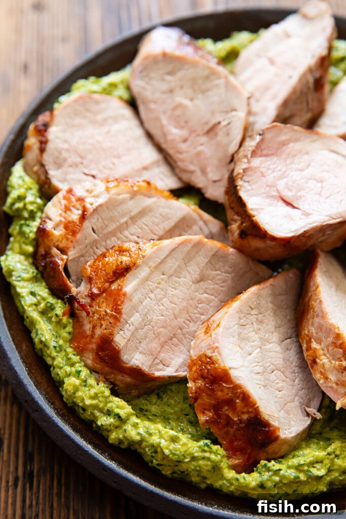 Grilled Pork Tenderloin with Green Romesco 2 Close up image of pork tenderloin with green romesco on a dark plate.