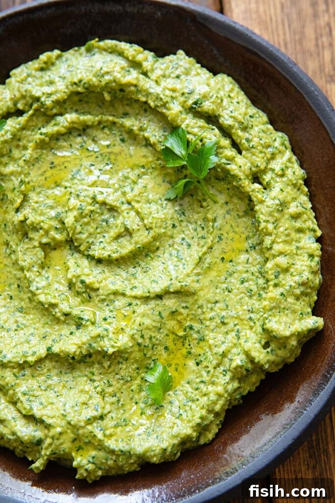 Green Romesco Sauce Recipe for Grilled Vegetables and Fish 3 Close up image of green sauce on a dark plate and background.