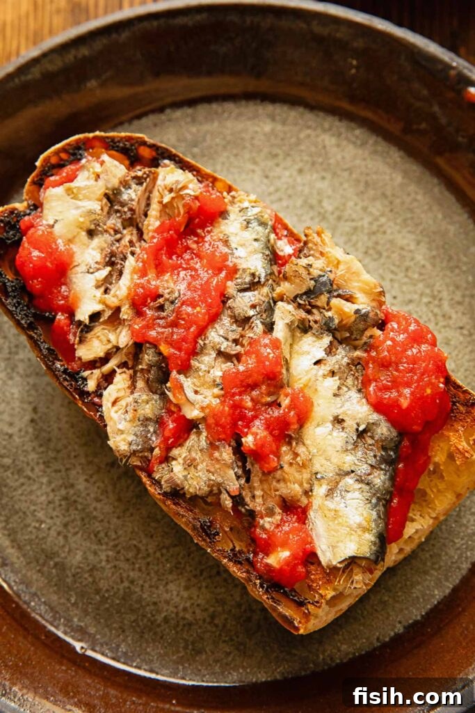 3 Sardine Toast Recipes: Flavorful Ideas for Any Meal 2 Toast on a dark plate with sardines and tomatoes.