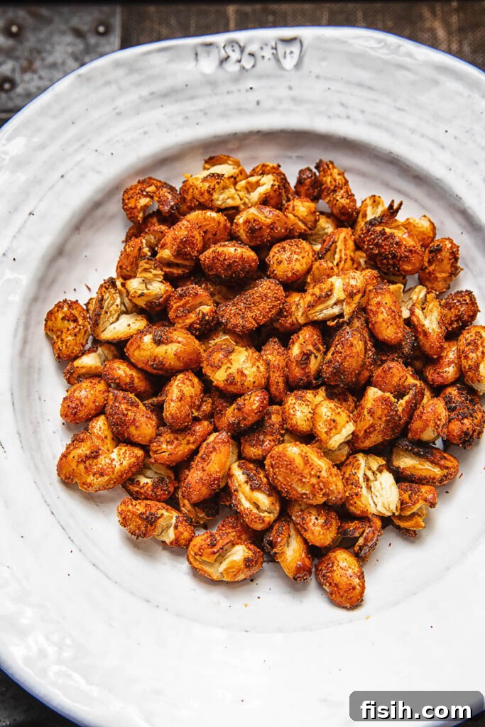 Crispy Butter Beans in the Air Fryer 2 A pile of spiced butter beans on a white plate against a wood background.